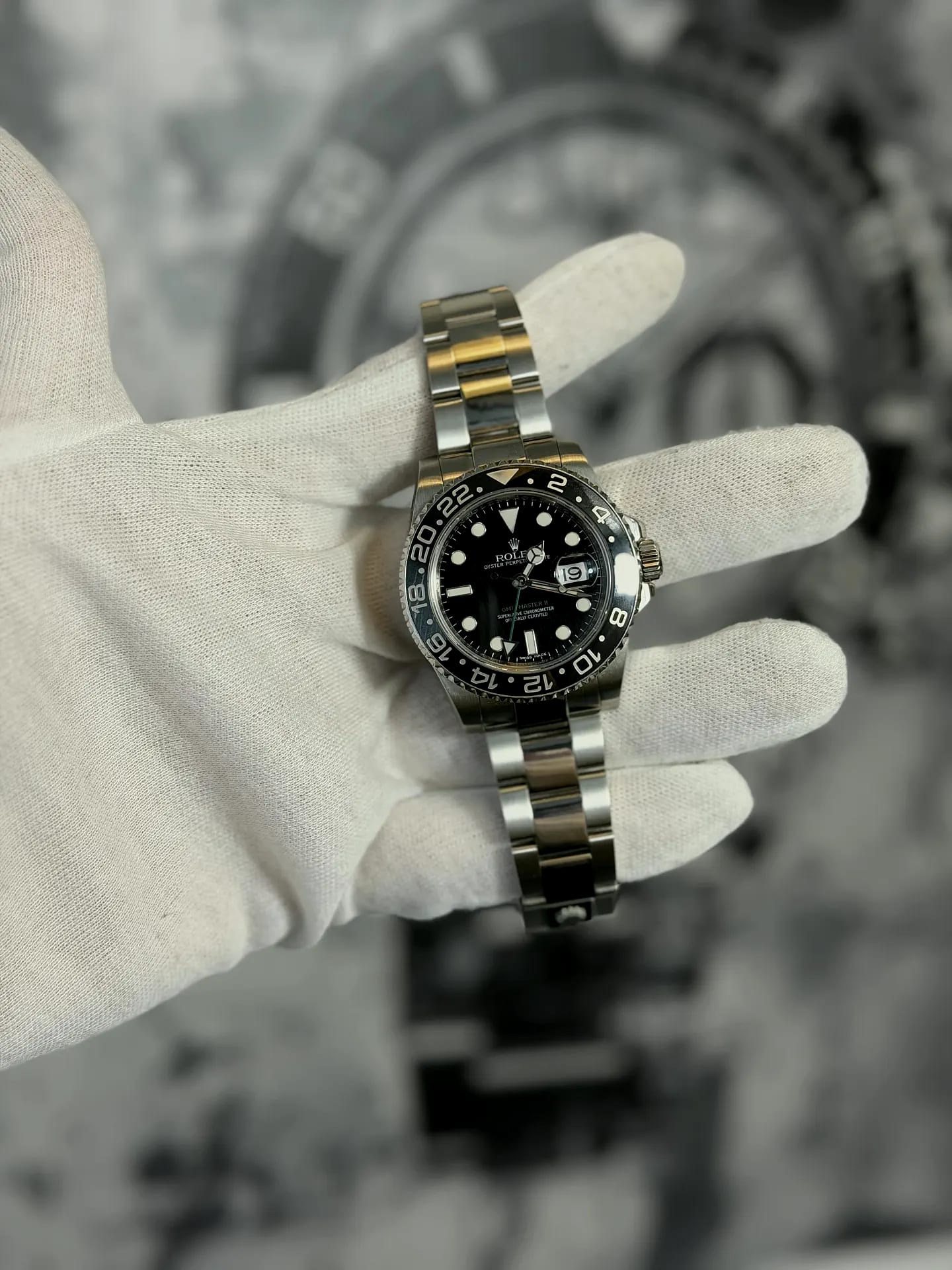 A two-tone steel and gold Rolex GMT-Master II held in a white cotton glove