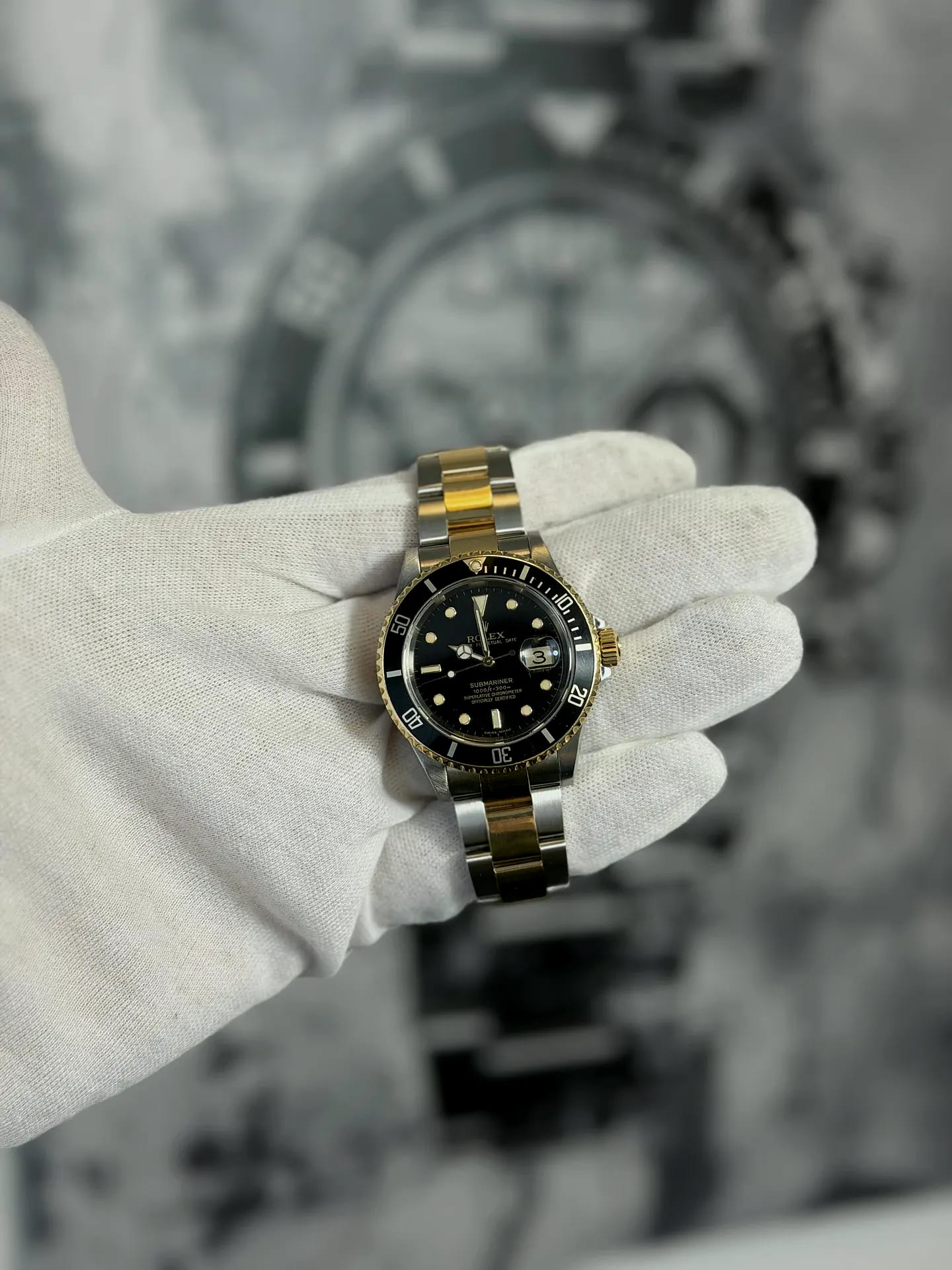A two-tone steel and gold Rolex Submariner Date held in a white cotton glove