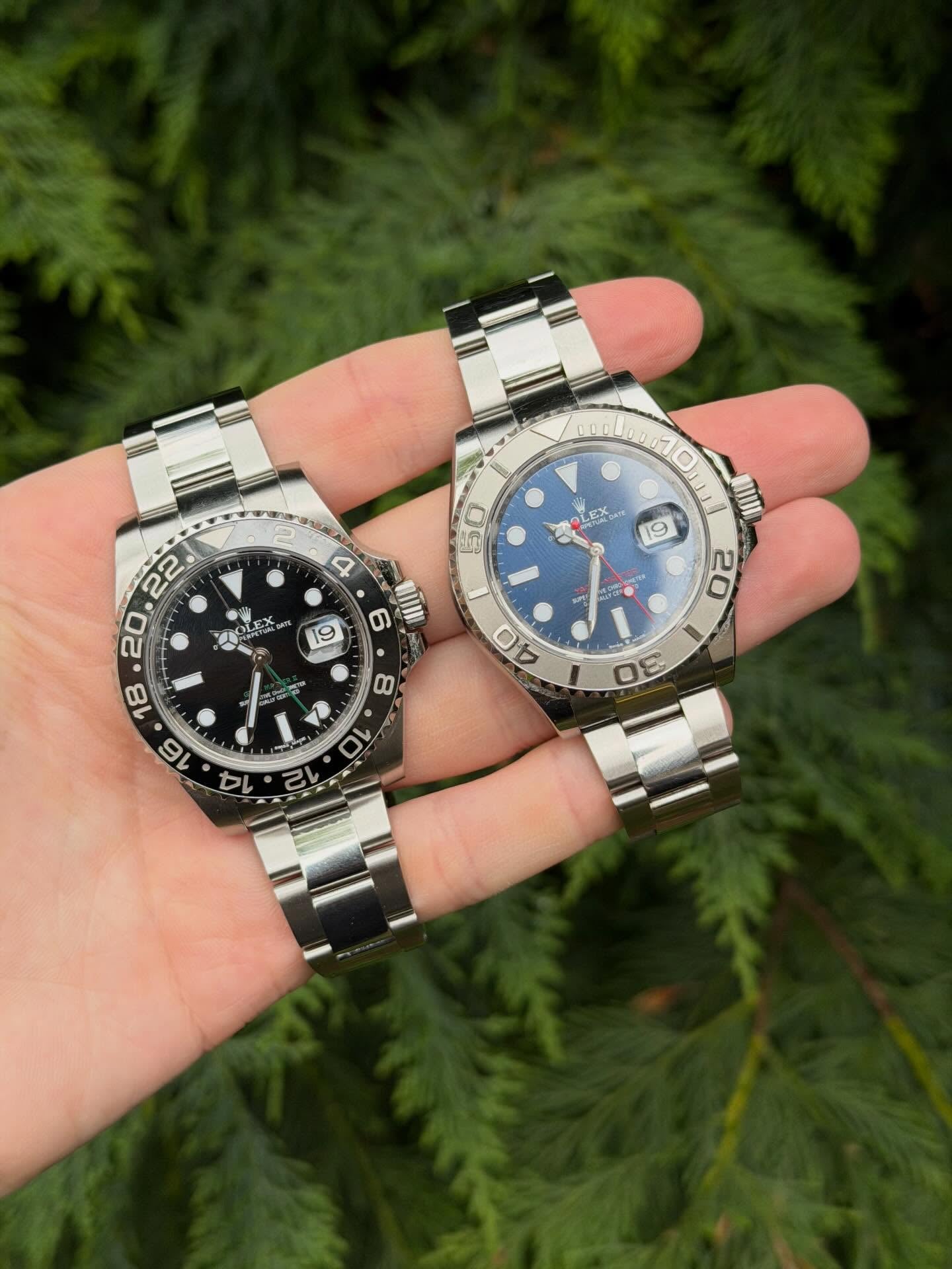 A Rolex GMT-Master II and a blue-dial Yacht-Master held in hand