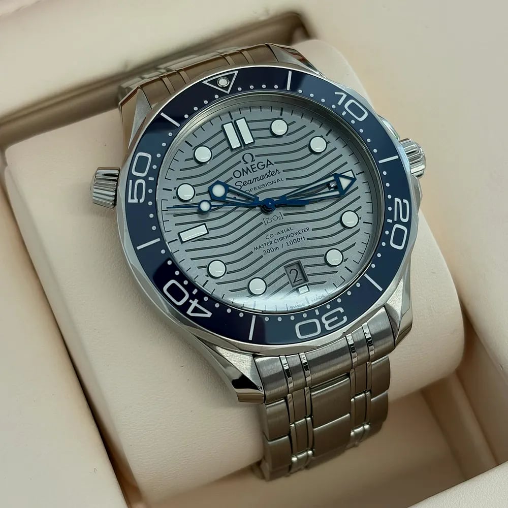 An Omega Seamaster Diver 300M with a blue bezel and grey wave dial on a steel bracelet, in its box